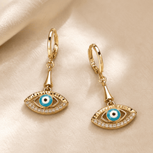The Side-Eye Charm Drops — Gold Plated Evil Eye Drop Earrings by House of Zena, worn on model